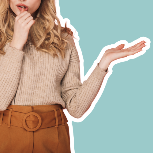 Vrouw in neutrale outfit met beige trui en roestbruine broek tegen een blauwe achtergrond, als visuele metafoor voor het ontdekken van je kleurtype via een kleurenanalyse. Beeld bij blog over kleuradvies en persoonlijke stijlkeuzes.