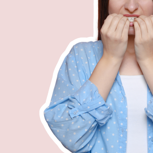 Vrouw in een lichtblauwe blouse met stippen, zenuwachtig bijtend op haar nagels – symbolisch voor de twijfel of het combineren van prints en kleuren niet te druk wordt. Beeld bij blog over kleurenanalyse en stylingtips.